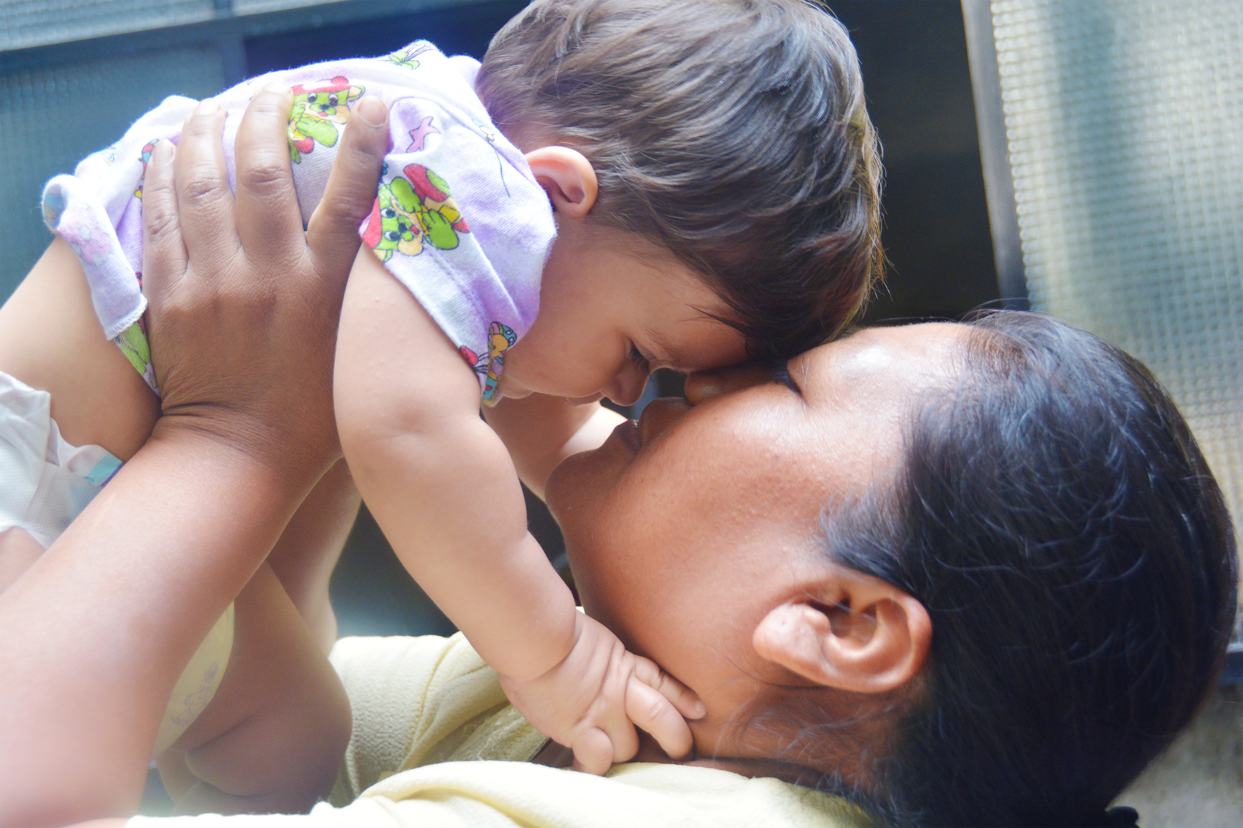 Woman holding baby above her head about to kiss her